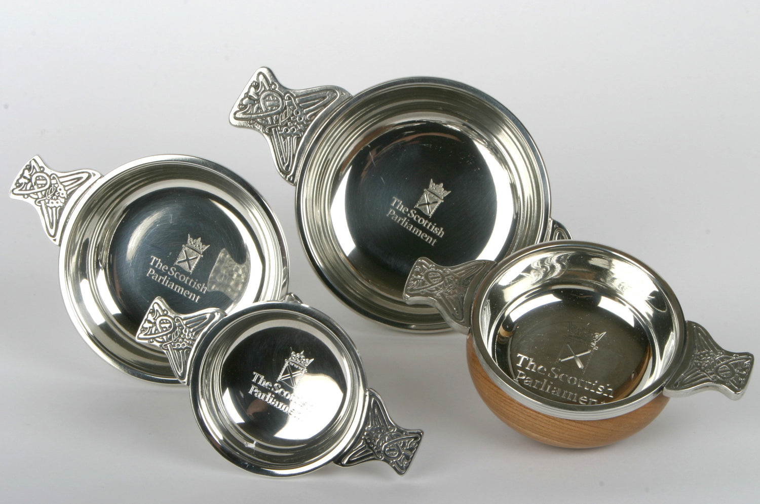 Four quaichs in different sizes, engraved with the symbol of the Scottish Parliament.