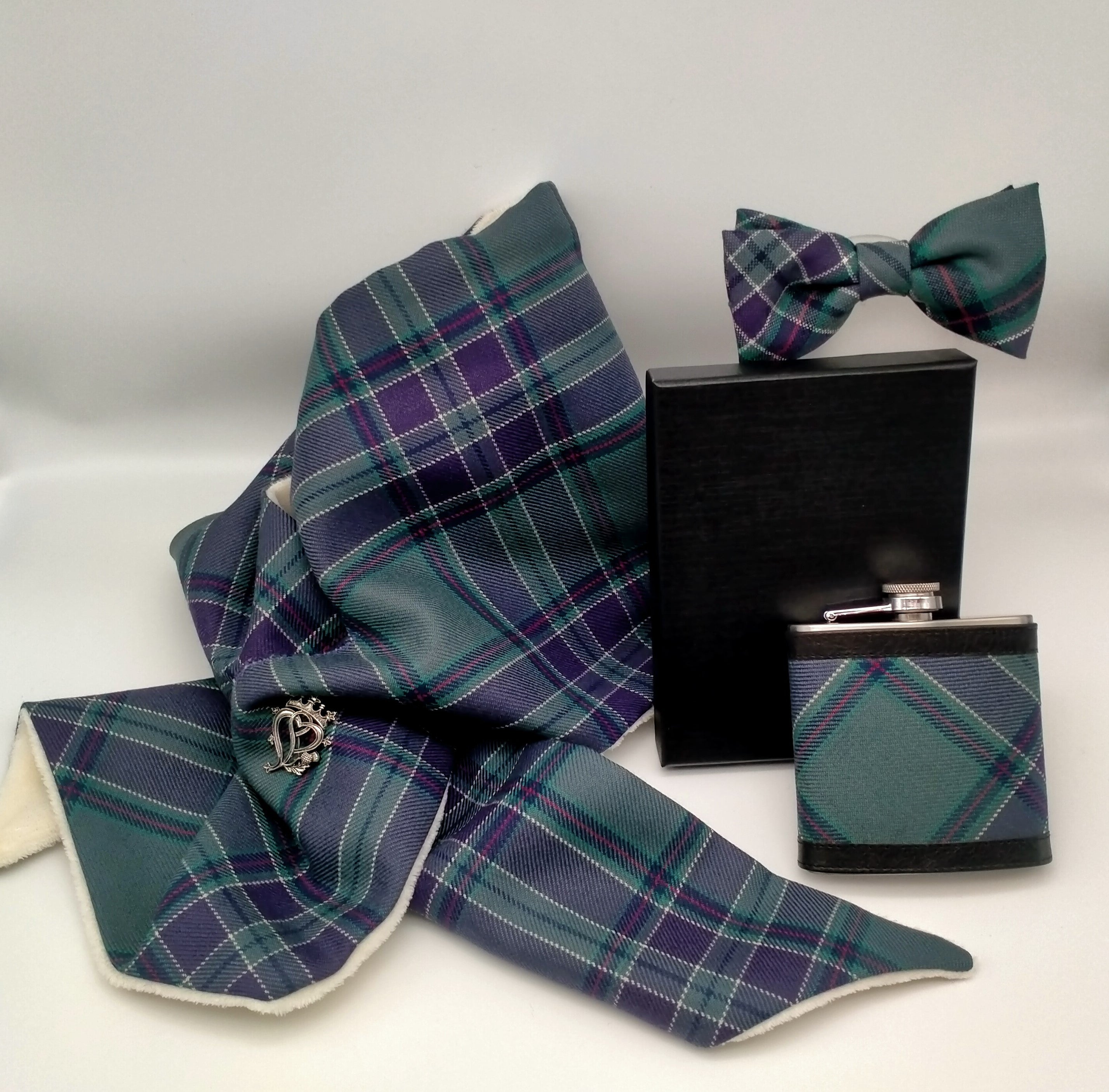 An image showing a scarf, a bow-tie and a hip flask in the Scottish Parliament tartant arranged together.