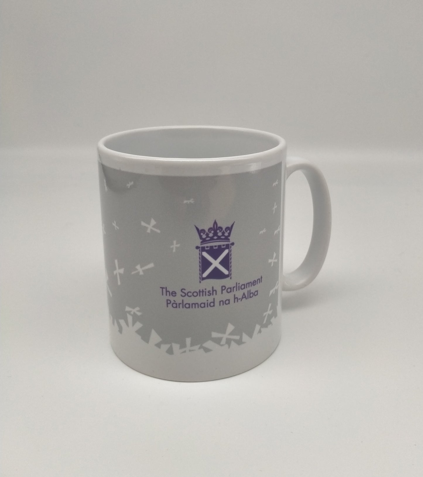 White mug printed with with white Parliament symbol and saltires on grey background.