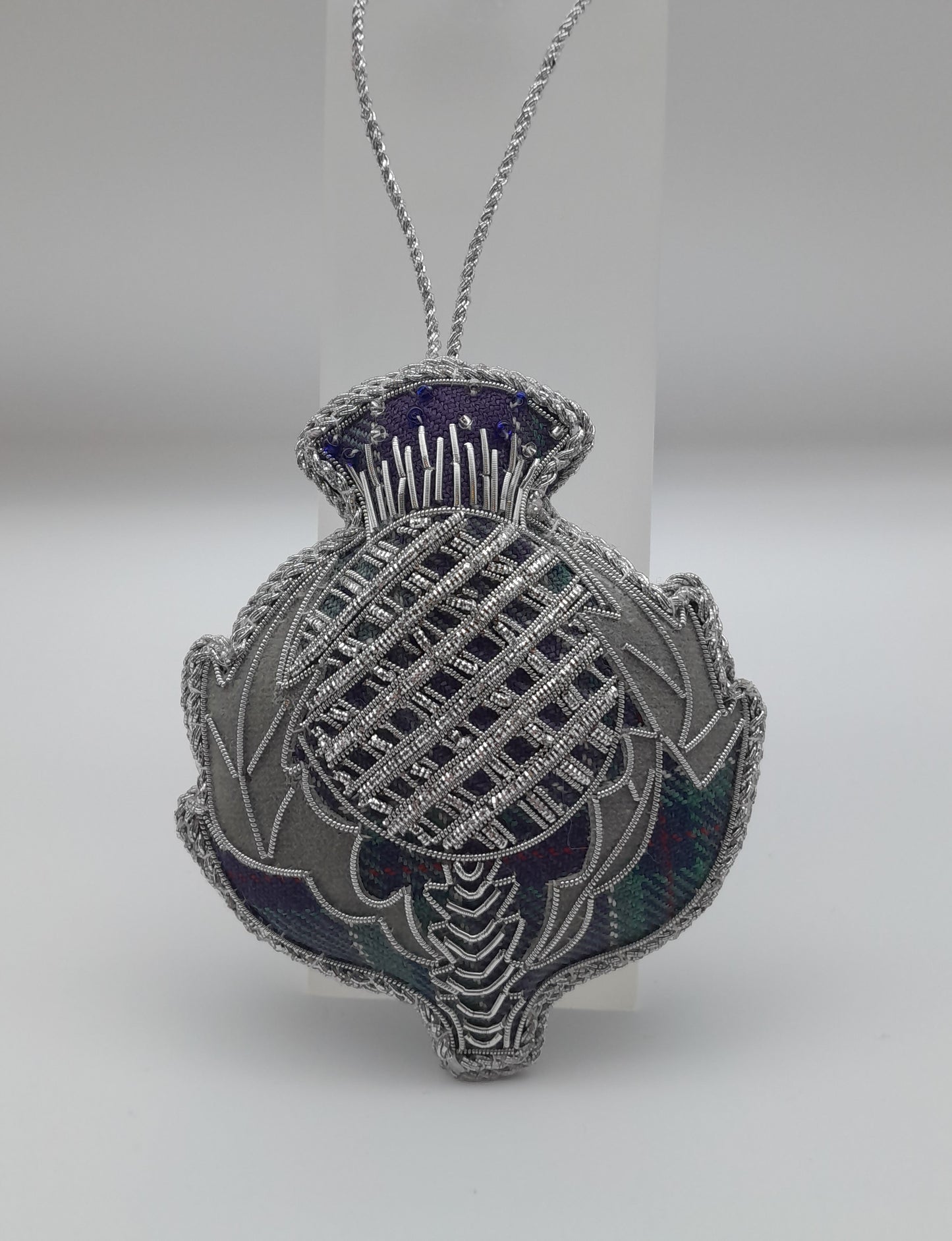 Shape of thistle. background fabric tartan with silver thread and bead embellishments.