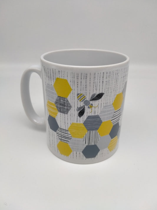 White mug with hexagonal honeycomb and bee design. Grey, black, gold and teal tones.