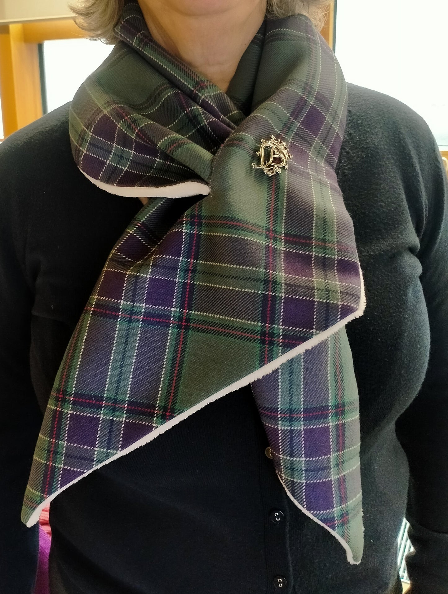 A scarf worn by a female model over a navy cardigan.