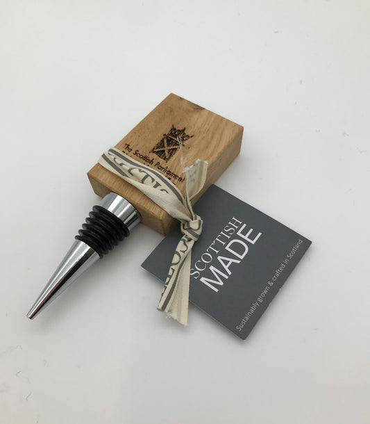 The bottle stopper with the oak top engraved with the symbol of the Scottish Parliament. Tied with a ribbon with a black label attached.
