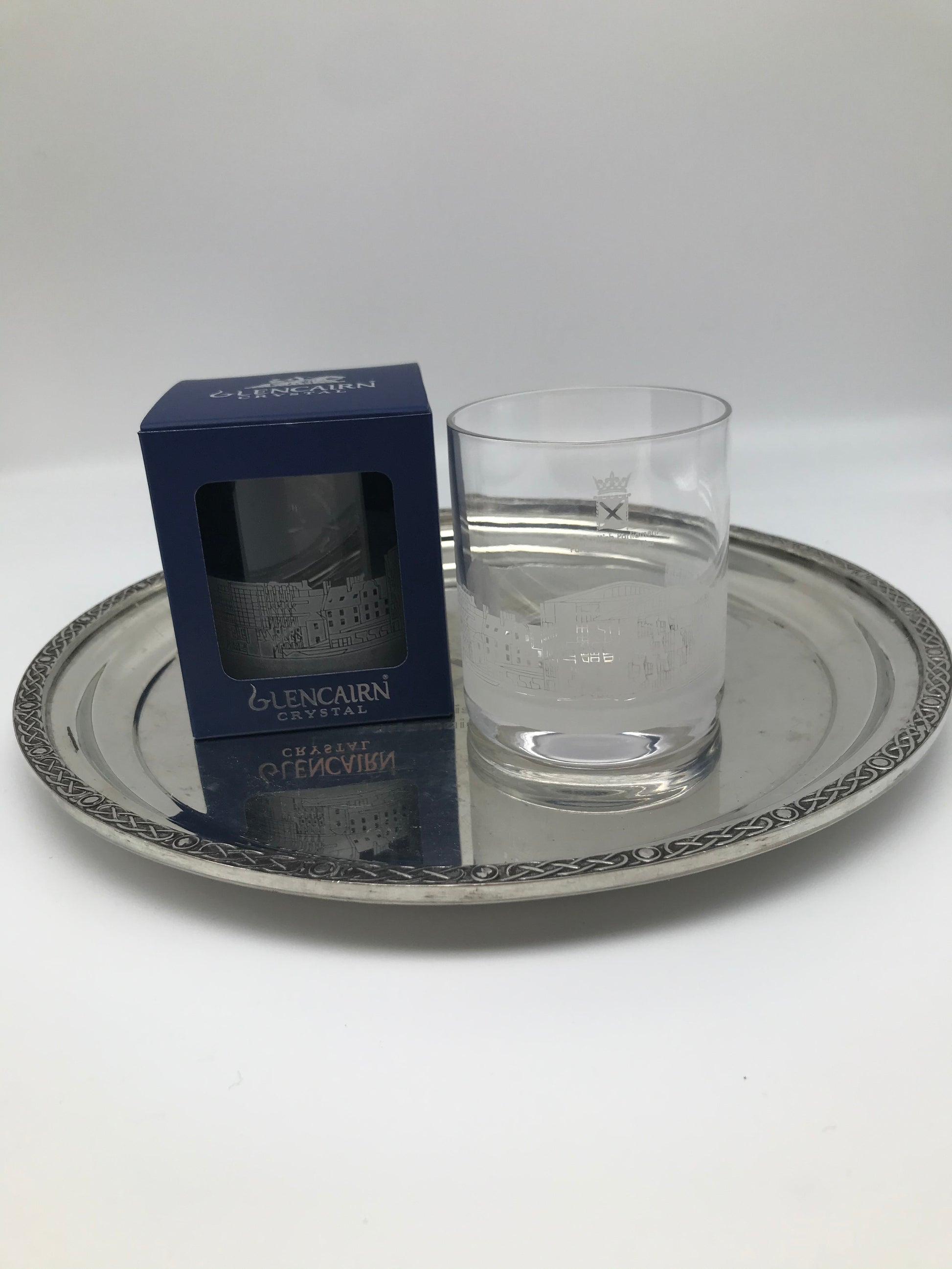 Two glasses, one in the box and one without it placed on a silver metal tray.