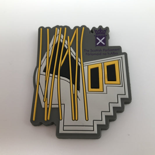 MSP window shaped magnet. shades of grey with gold highlights. Purple symbol of Parliament.