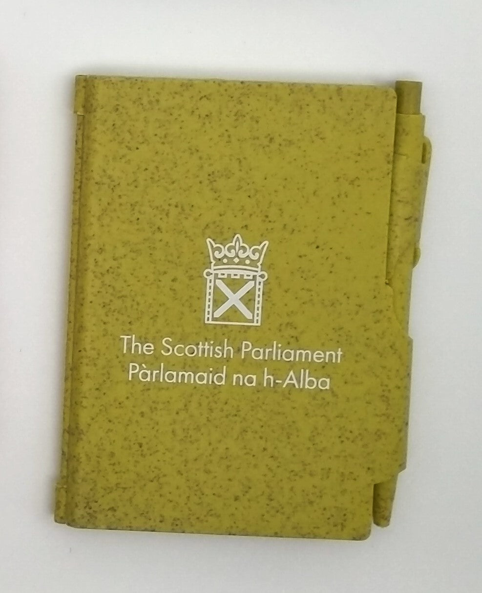 A lime green notebook with the symbol of the Scottish Parlaiment in white and a matching pen slid into a holder on the side.