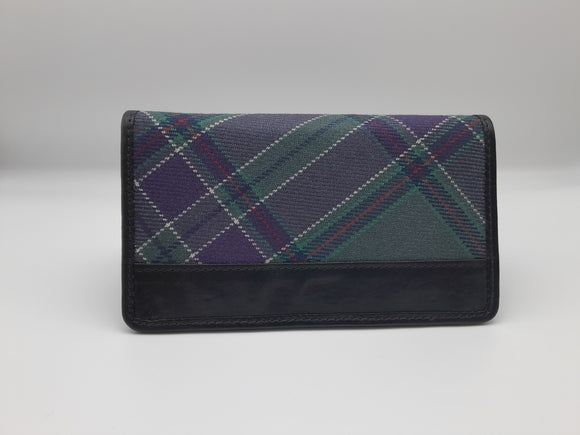 Rectangular purse made of the parliament tartan and black leather. Closed.