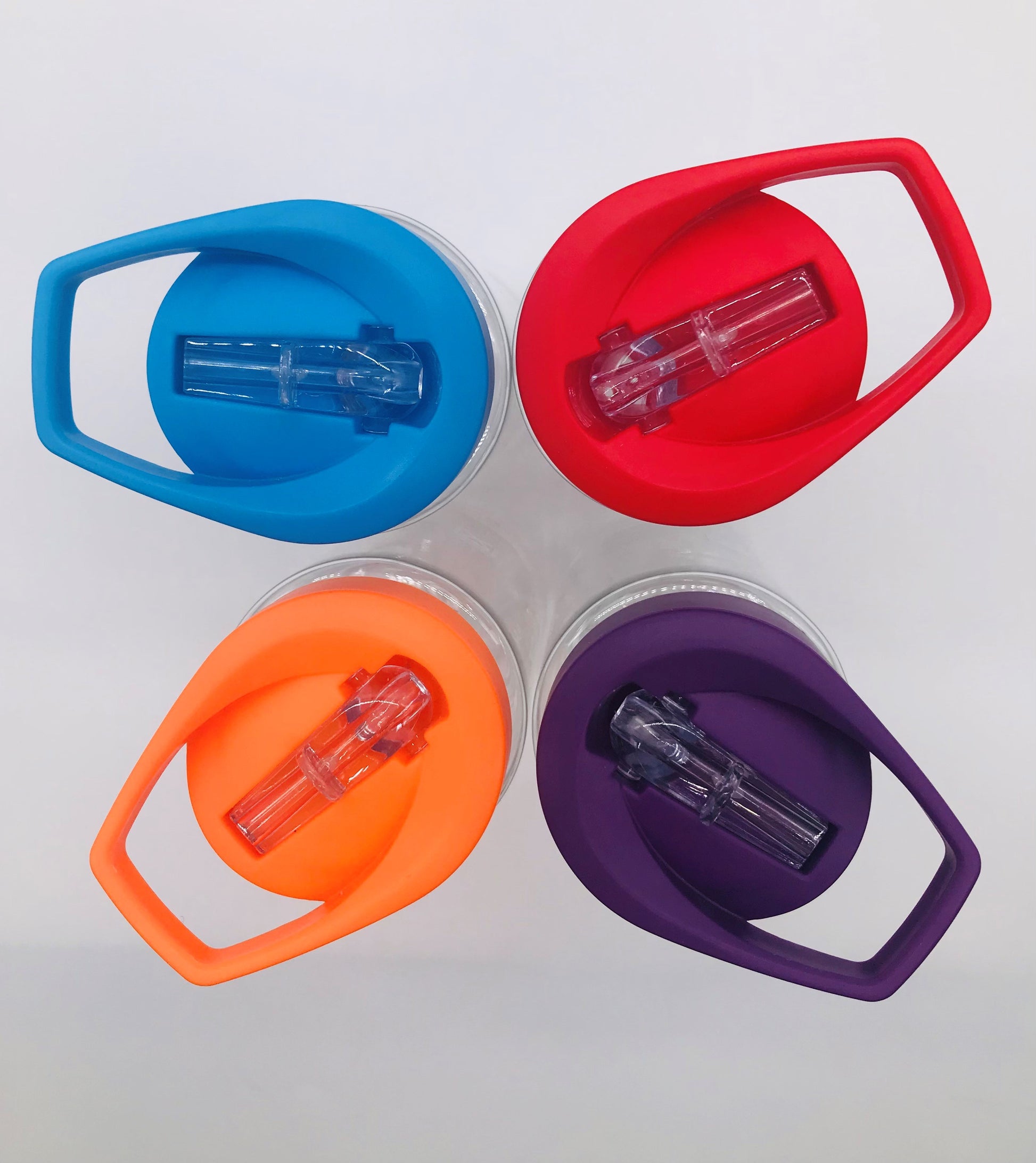 An overhead view of four plastic bottles. Their lids have foldable spouts for drinking and are each a different colour. There is one blue, one red, one purple, and one orange.