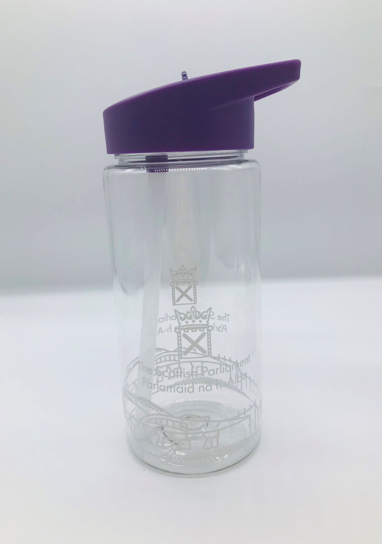 A clear plastic bottle with internal straw. it has the Scottish Parliament logo and outline of the parliament building painted around the circumference of the bottle. Its lid is purple