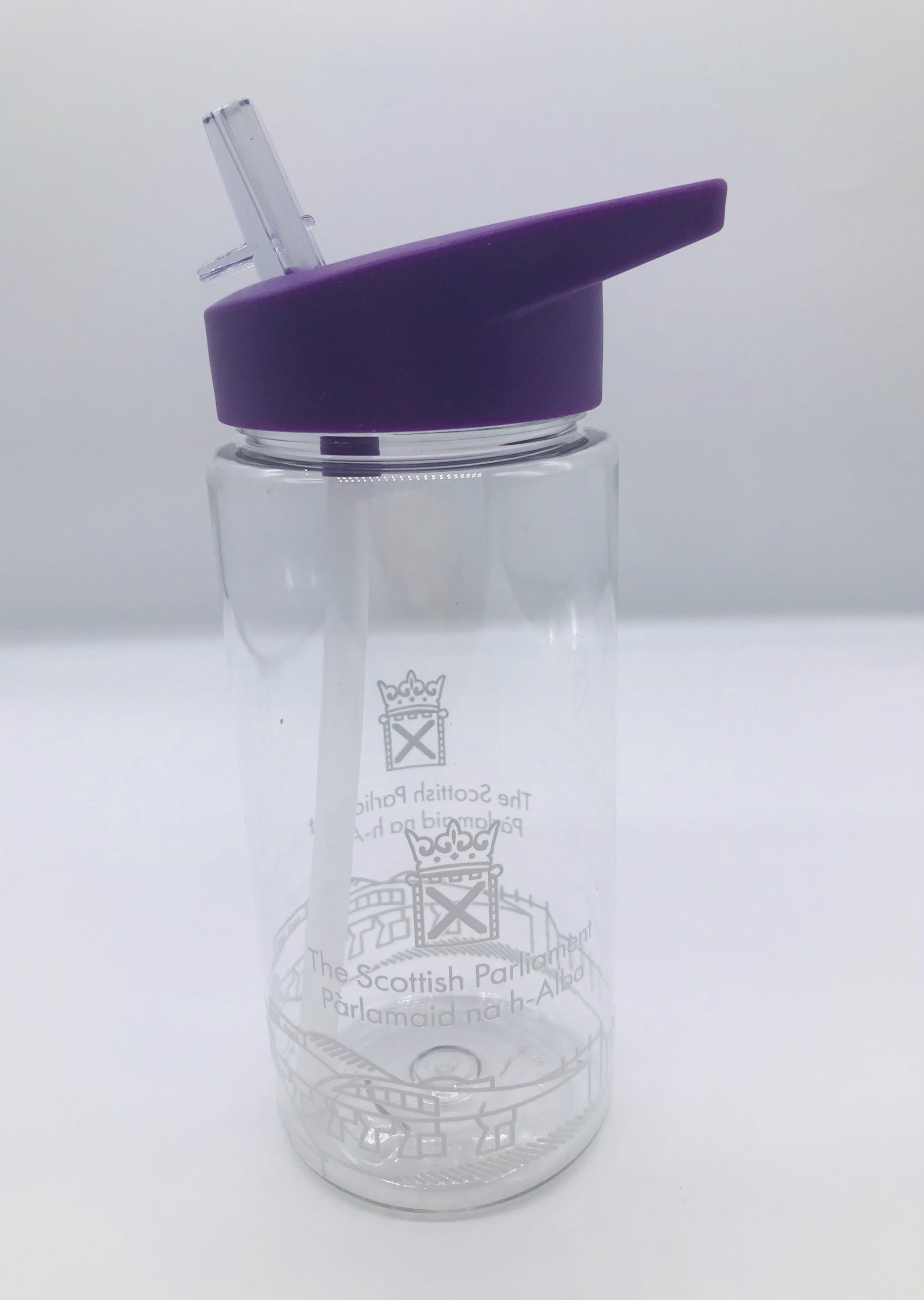 A clear plastic bottle with internal straw. it has the Scottish Parliament logo and outline of the parliament building painted around the circumference of the bottle. Its lid is purple in colour and has a foldable spout.