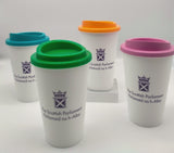 Four white cups with lids in different colours. Decorated with the symbol of the Scottish Parliament in purple. 