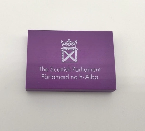 Purple rectangular eraser with a white symbol of the Scottish Parliament. 