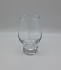 A small tulip shaped whisky glass decorated with the symbol of the Scottish Parliament.