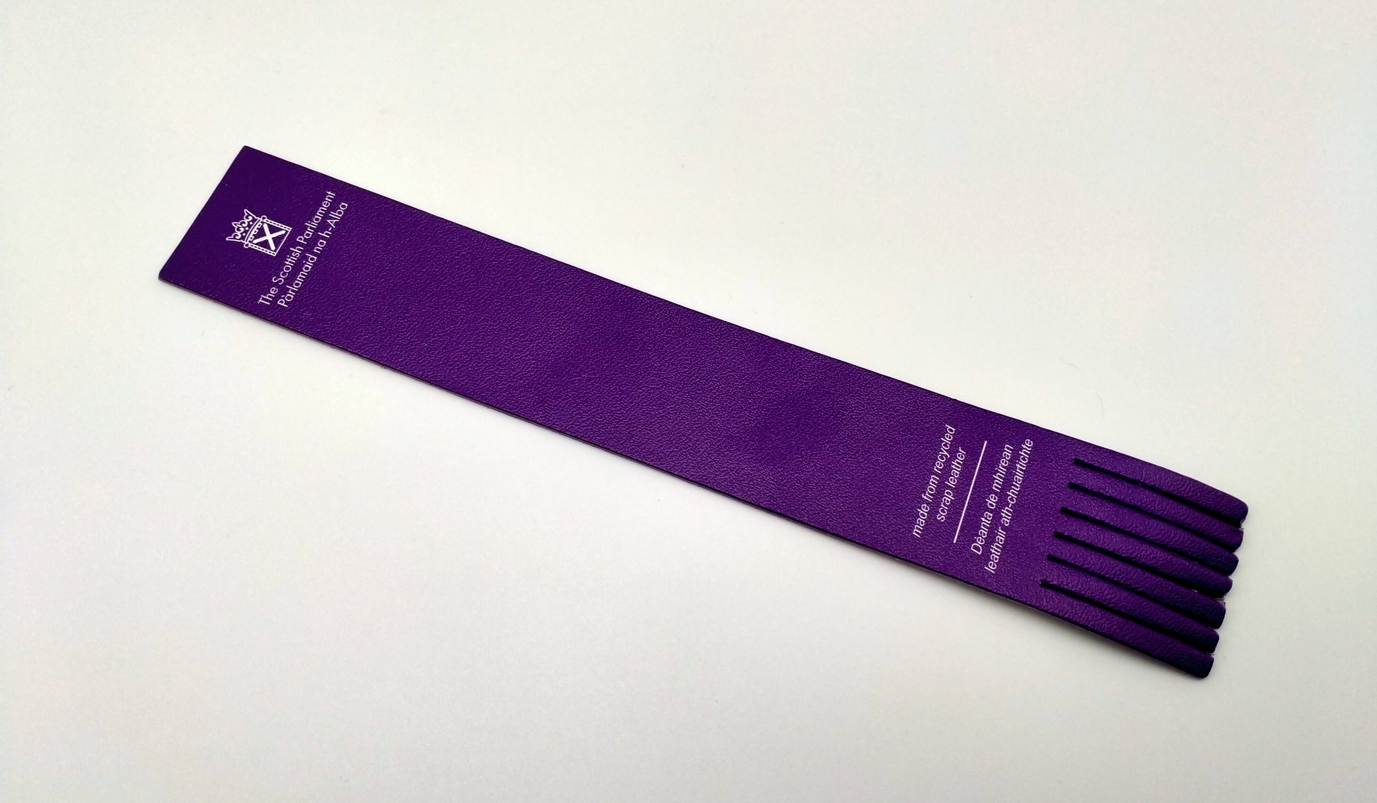 A purple leather bookmark with fringing on the bottom. 