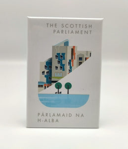A white magnet printed with an image of a part of the Scottish Parliament building. A contemporary design features some architectural details of the building, a pond and trees. Writing The Scottish Parlaiment in English and Gaelic.