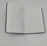 Open notebook showing lined pages and a white ribbon for marking pages.