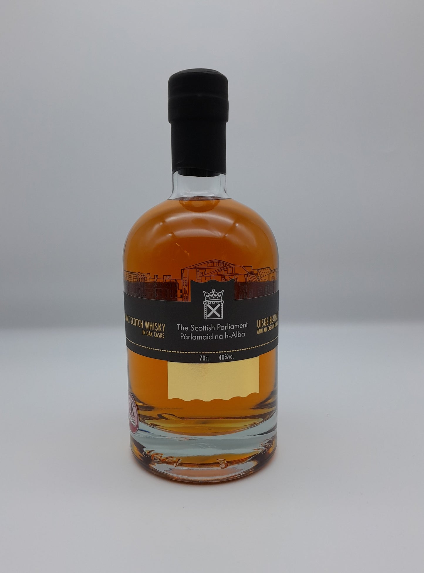 A 70cl bottle of whisky with a black label printed with the symbol of the Scottish Parliament.