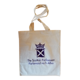 Square bag. Natural cotton colour featuring the parliament symbol printed in purple. Long handles.