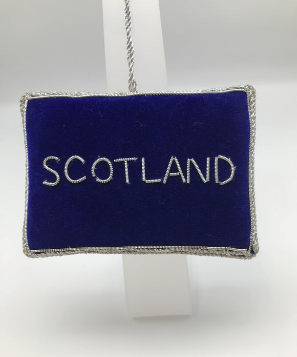 Rectangular decoration in dark blue fabric with Scotland embroidered in silver and silver stitching. 