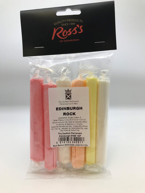 six sticks of Edinburgh rock in pink, white, orange and yellow colours, in original packaging with a label..
