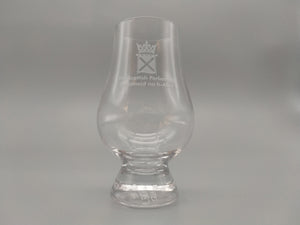 A tulip shaped whisky glass decorated with the symbol of the Scottish Parliament.