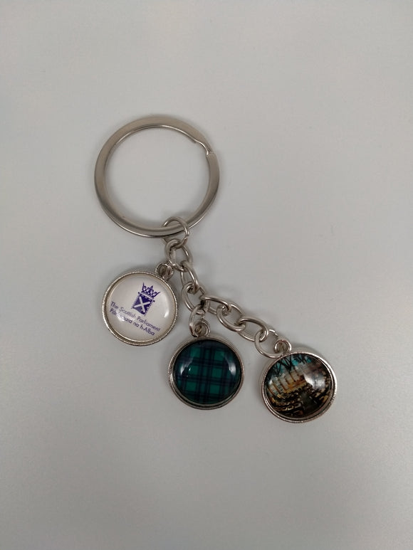 A keyring with a metal chain and three round charms attached, showing pictures of the Debating Chamber, the official parliament tartan and the symbol of the Scottish Parliament.