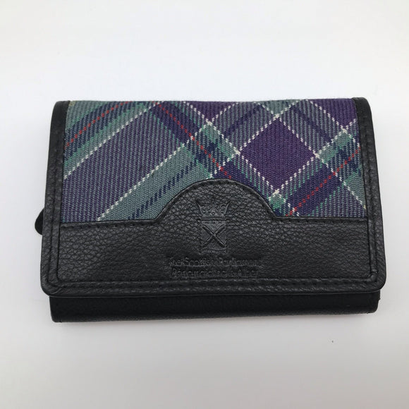 Rectangular purse made of the parliament tartan and black leather decorated with the symbol of the Scottish parliament. Closed. 