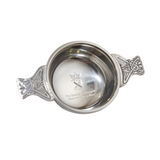 Silver coloured round quaich with handles featuring a Celtic knot design.  Bowl engraved with the Parliament symbol.