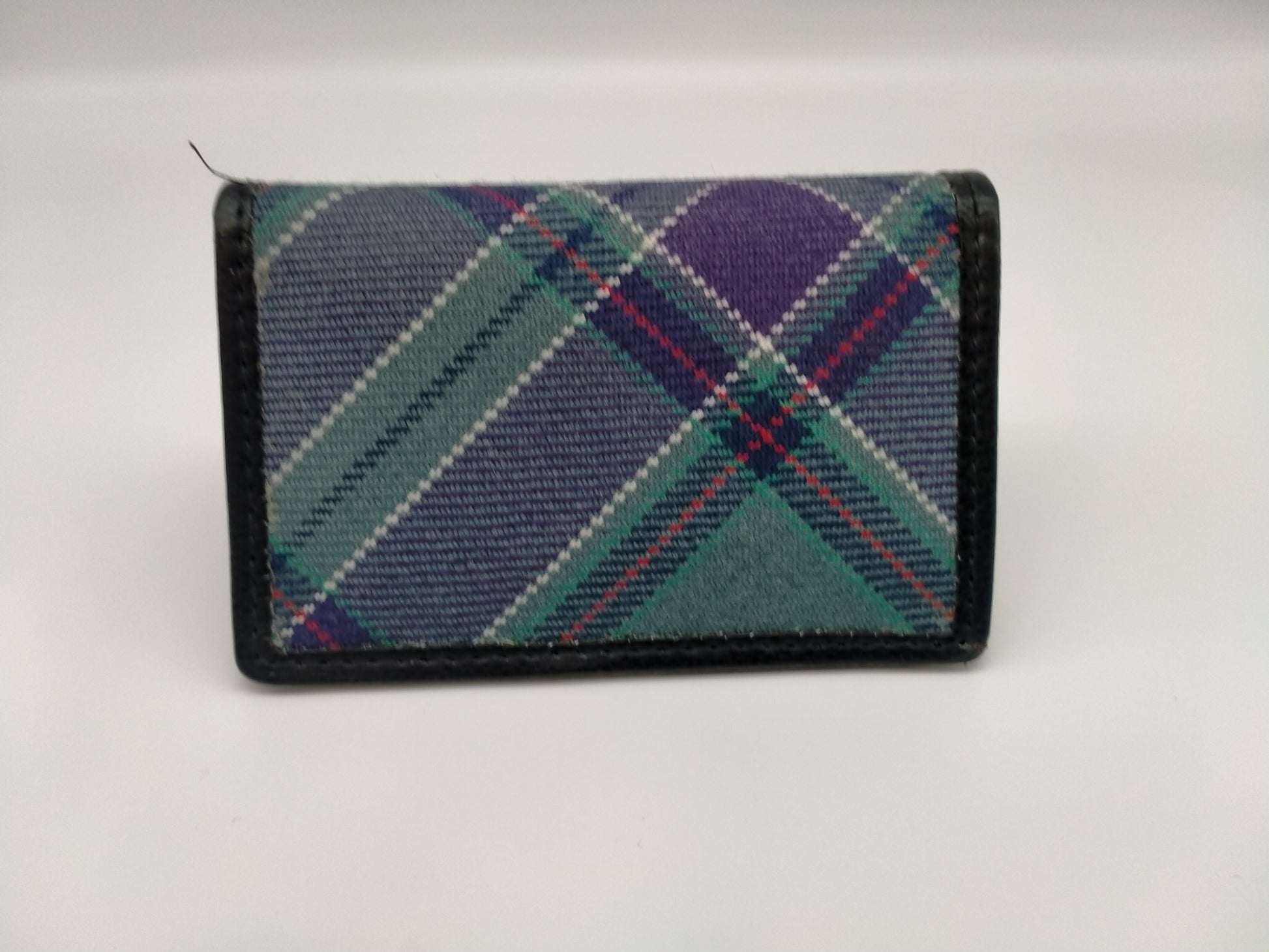 Rectangular card case in tartan with leather edging. 